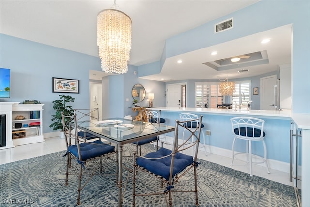 dining room with a tray ceiling, light tile patterned flooring, and a chandelier