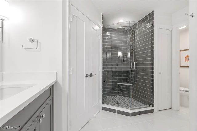 bathroom featuring walk in shower, vanity, toilet, and tile patterned floors