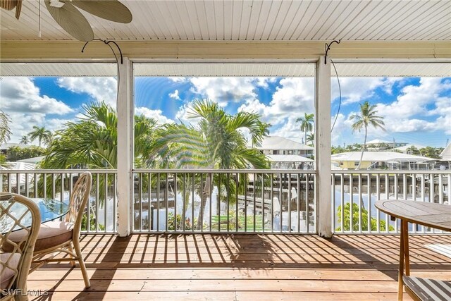 unfurnished sunroom featuring a water view and ceiling fan