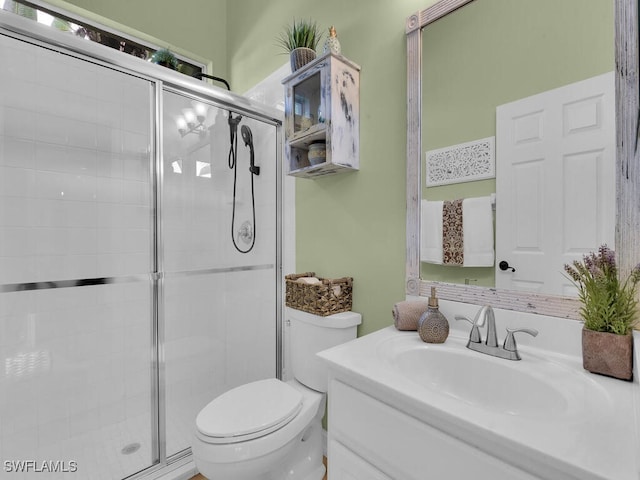 bathroom with vanity, toilet, and a shower with door