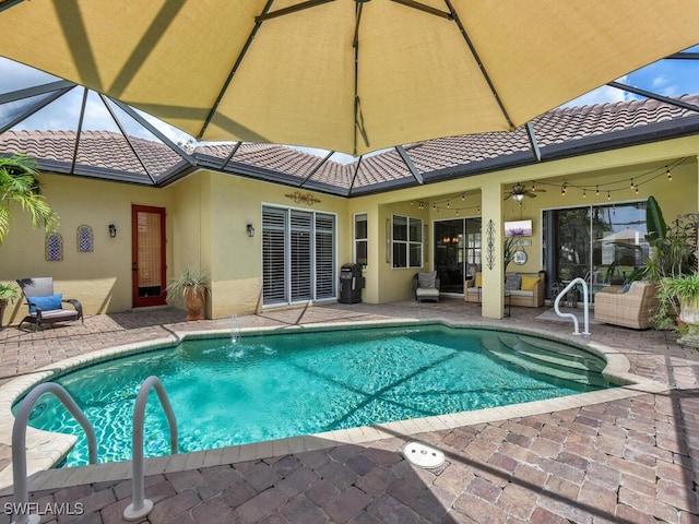 view of pool featuring ceiling fan, glass enclosure, and a patio area