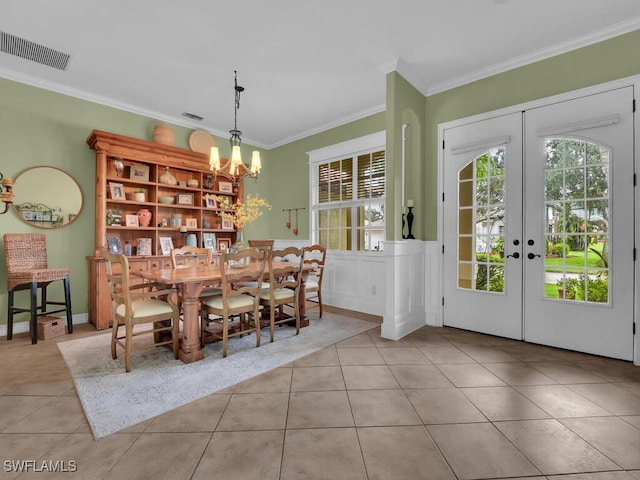 dining space featuring french doors, an inviting chandelier, crown molding, and light tile patterned floors