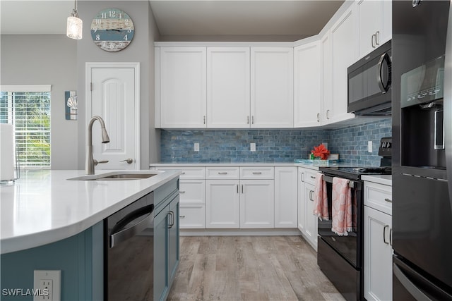 kitchen featuring white cabinetry, pendant lighting, black appliances, light hardwood / wood-style flooring, and sink