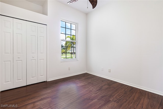 unfurnished bedroom with dark wood-type flooring, a closet, and ceiling fan