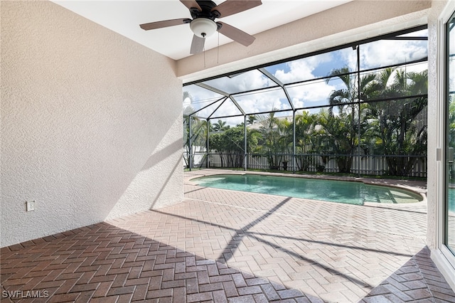 view of swimming pool with a lanai, ceiling fan, and a patio