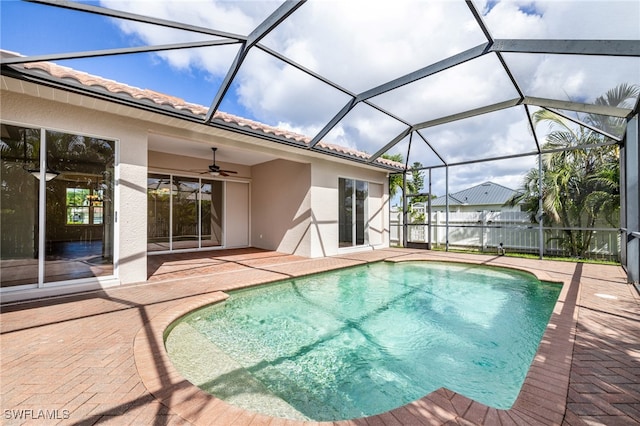 view of swimming pool featuring glass enclosure, ceiling fan, and a patio area