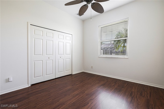 unfurnished bedroom with dark wood-type flooring, ceiling fan, and a closet