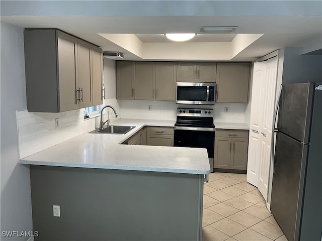 kitchen featuring appliances with stainless steel finishes, light tile patterned floors, kitchen peninsula, and sink