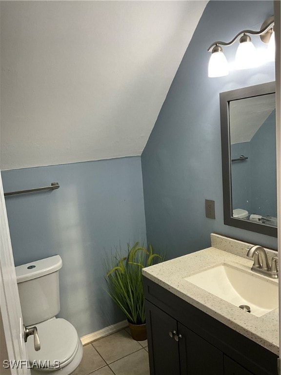 bathroom featuring vanity, toilet, vaulted ceiling, and tile patterned floors