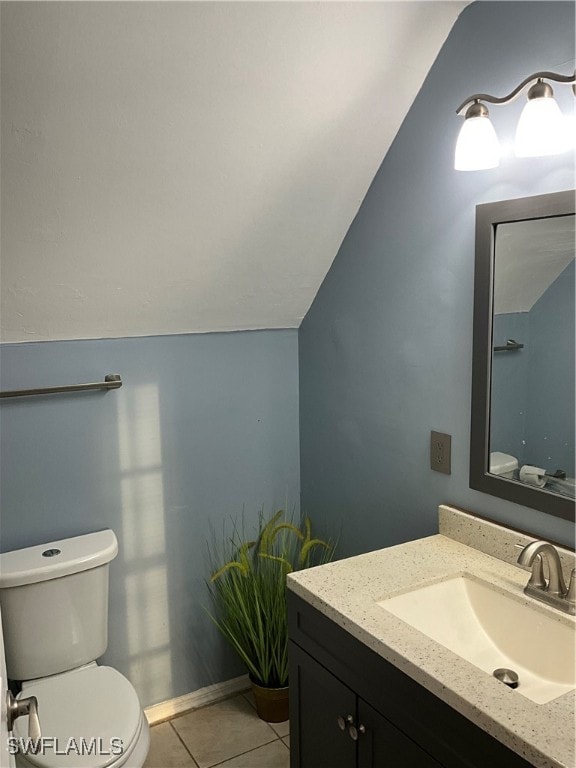 bathroom with vanity, toilet, tile patterned floors, and lofted ceiling