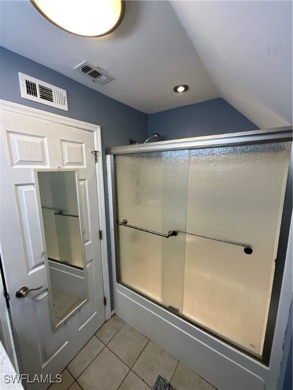 bathroom featuring a shower with shower door, vaulted ceiling, and tile patterned floors