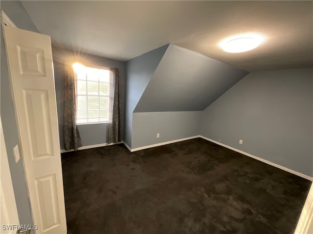 bonus room featuring lofted ceiling and dark colored carpet