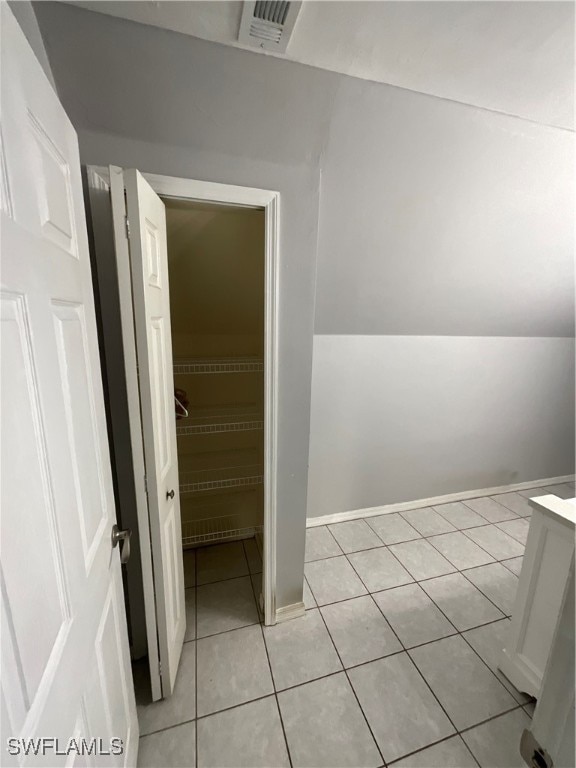 bathroom with vaulted ceiling and tile patterned floors