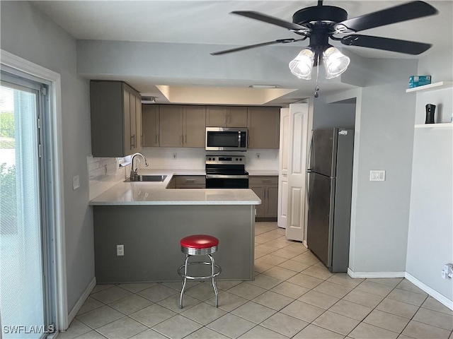 kitchen featuring a sink, a peninsula, light tile patterned flooring, and stainless steel appliances