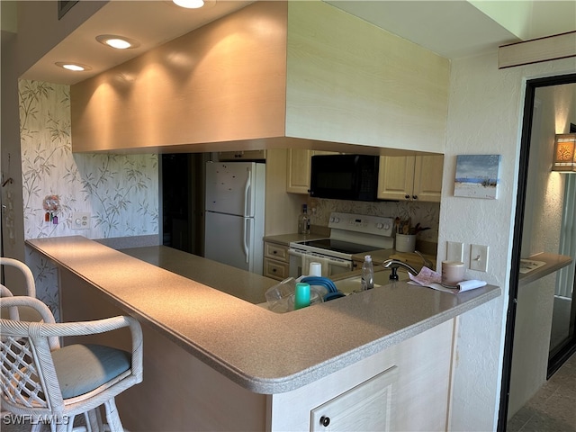 kitchen featuring kitchen peninsula, sink, white appliances, and a breakfast bar area