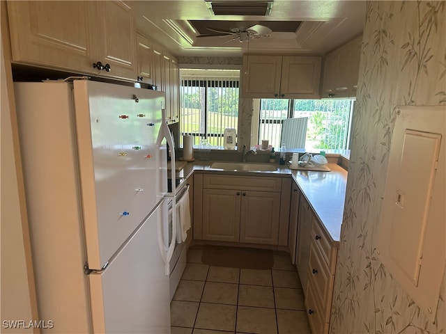 kitchen with stainless steel range, light tile patterned floors, sink, white refrigerator, and a raised ceiling