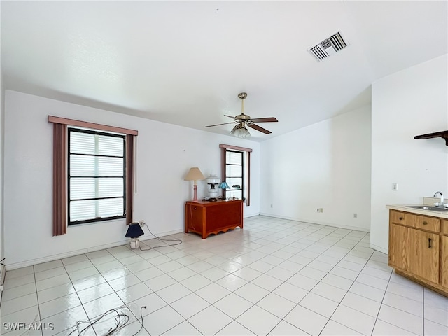 unfurnished living room with light tile patterned flooring, ceiling fan, sink, and a wealth of natural light