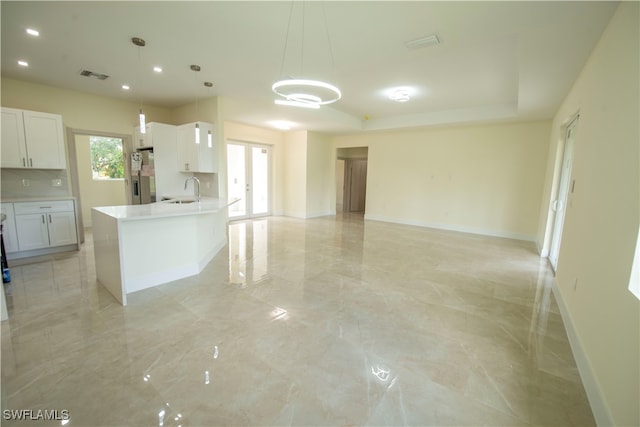 kitchen featuring stainless steel refrigerator with ice dispenser, sink, pendant lighting, and white cabinets