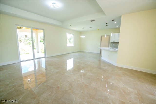 unfurnished living room with a tray ceiling and sink