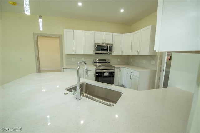 kitchen with sink, white cabinetry, decorative backsplash, appliances with stainless steel finishes, and decorative light fixtures