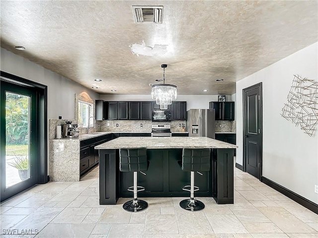 kitchen with a kitchen island, stainless steel appliances, backsplash, and a breakfast bar