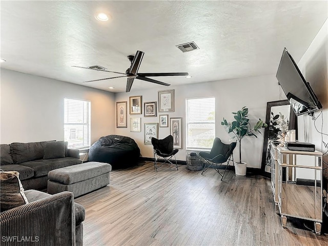 living room featuring ceiling fan, hardwood / wood-style floors, and a textured ceiling