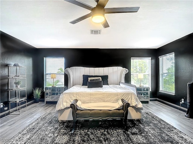 bedroom featuring ceiling fan, light hardwood / wood-style flooring, and multiple windows