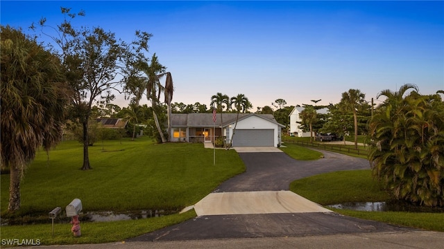 single story home featuring a garage and a lawn