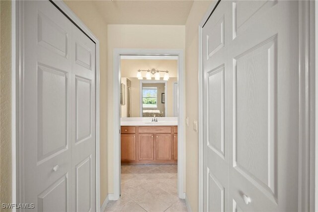 hallway featuring sink and light tile patterned floors