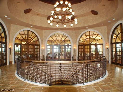 interior space featuring a raised ceiling, a high ceiling, and a notable chandelier