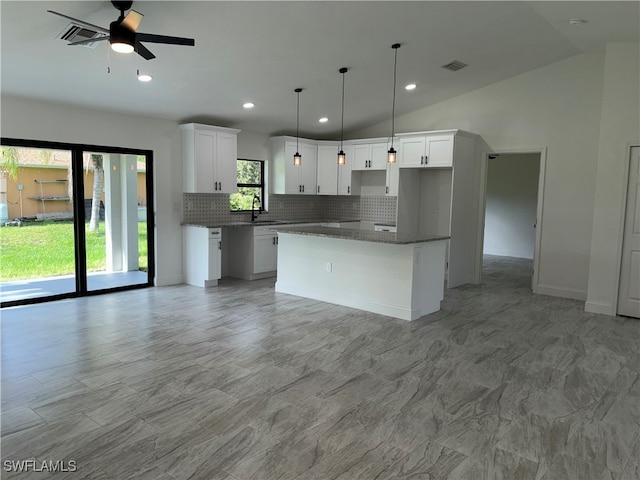 kitchen with white cabinetry, tasteful backsplash, a kitchen island, sink, and ceiling fan