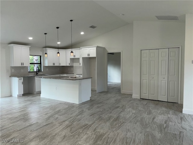 kitchen with a kitchen island, high vaulted ceiling, white cabinets, and tasteful backsplash