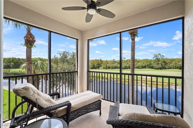 sunroom / solarium featuring plenty of natural light, ceiling fan, and a water view