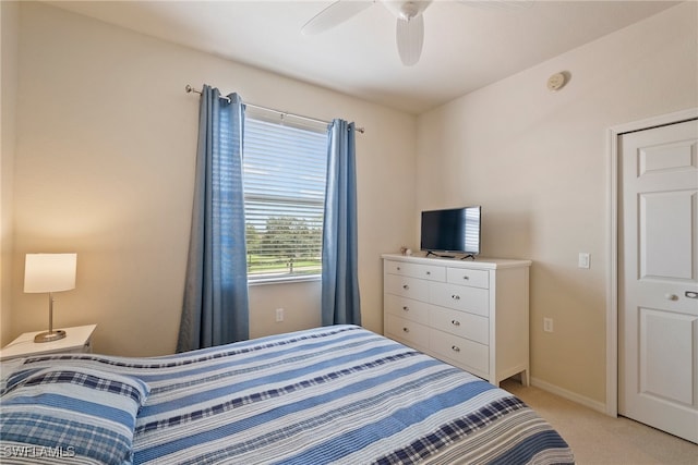 bedroom with a closet, ceiling fan, and light carpet