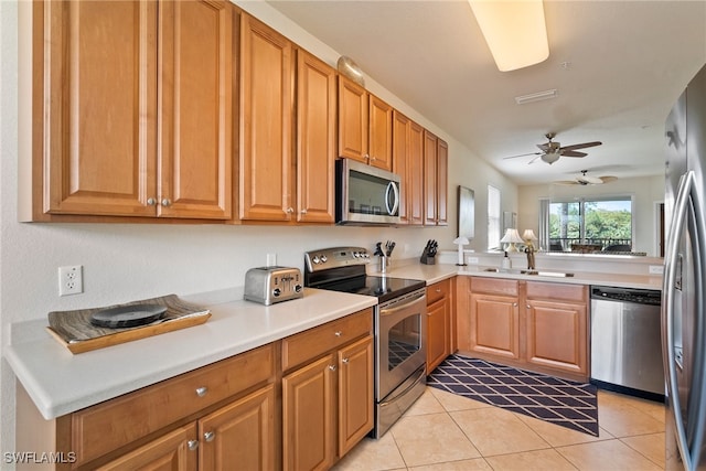 kitchen featuring light tile patterned floors, stainless steel appliances, sink, kitchen peninsula, and ceiling fan