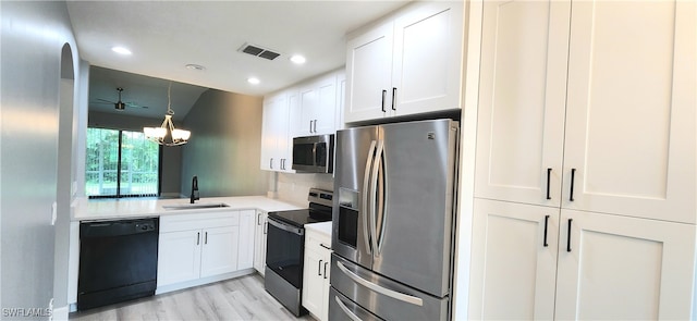 kitchen featuring appliances with stainless steel finishes, light hardwood / wood-style floors, white cabinets, an inviting chandelier, and sink