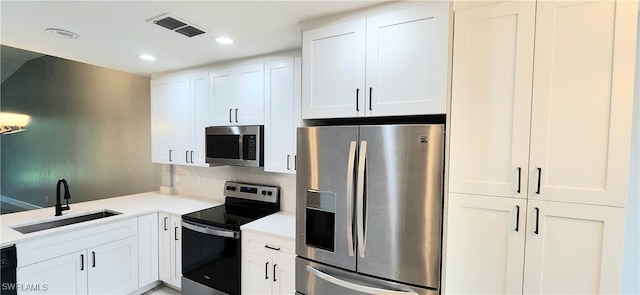 kitchen featuring appliances with stainless steel finishes, white cabinetry, and sink