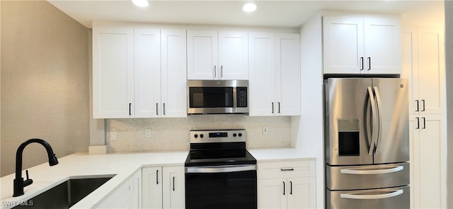 kitchen featuring stainless steel appliances, white cabinetry, tasteful backsplash, and sink