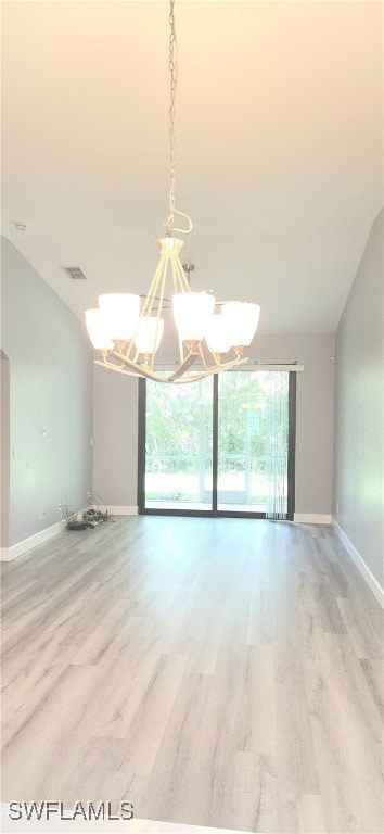 spare room featuring a notable chandelier, light hardwood / wood-style flooring, and vaulted ceiling