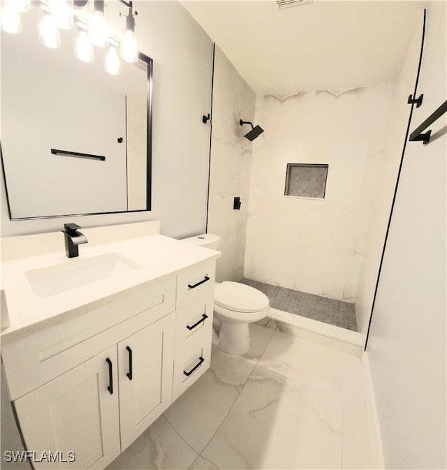 bathroom with a tile shower, vanity, and toilet