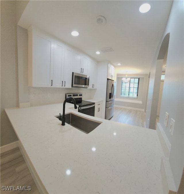 kitchen featuring light hardwood / wood-style floors, white cabinets, light stone countertops, stainless steel appliances, and sink