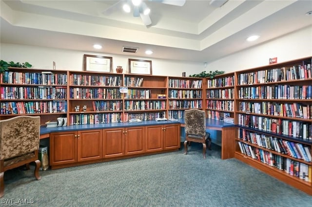 living area featuring carpet flooring, a tray ceiling, and ceiling fan