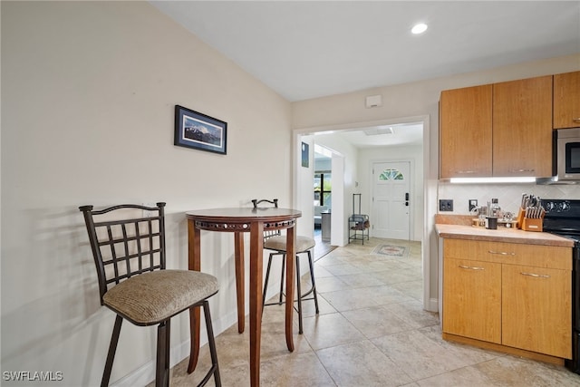 kitchen featuring decorative backsplash, light tile patterned flooring, and black range with electric cooktop