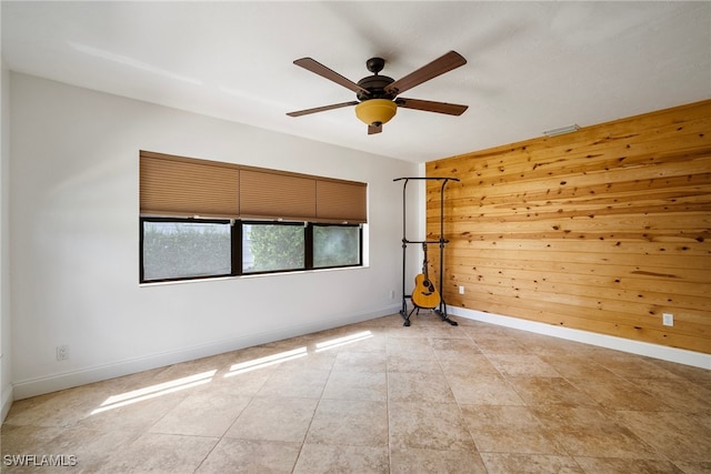 spare room with ceiling fan and wooden walls