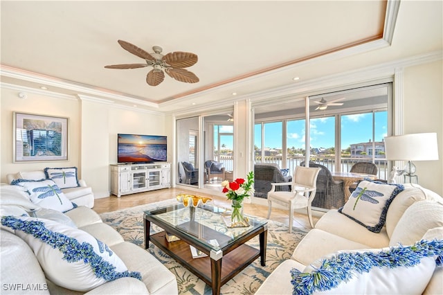 living room with ceiling fan, wood-type flooring, a raised ceiling, and ornamental molding