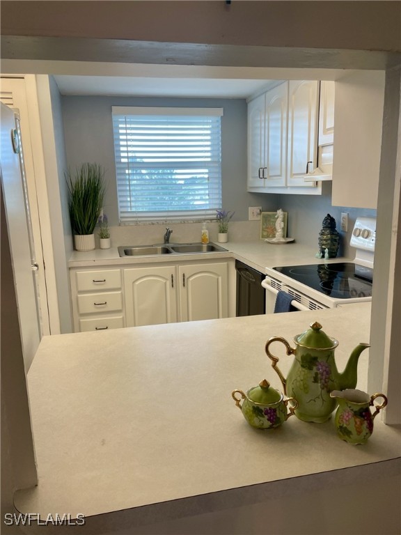 kitchen featuring white electric range oven, sink, white cabinets, and extractor fan