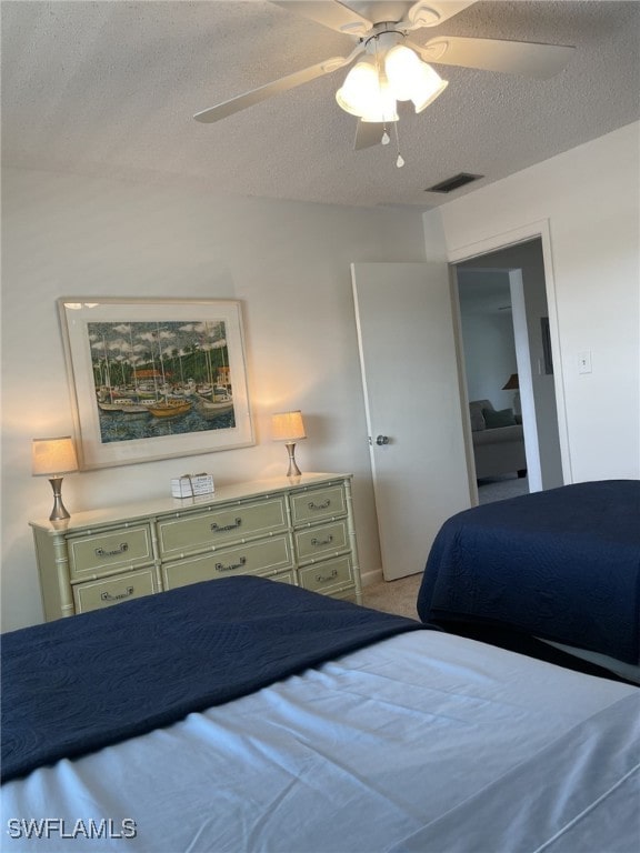 bedroom featuring light carpet, a textured ceiling, and ceiling fan