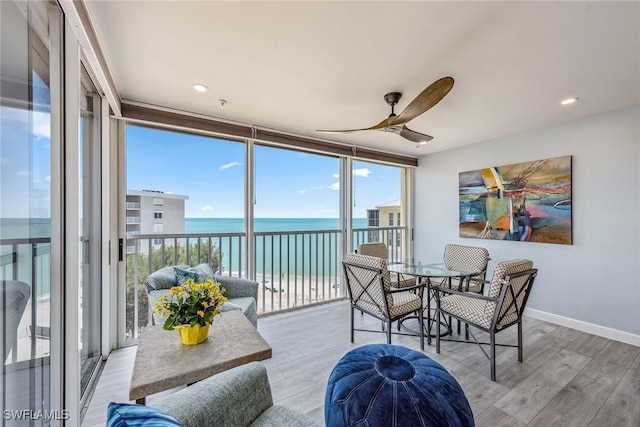 sunroom / solarium with a water view and ceiling fan