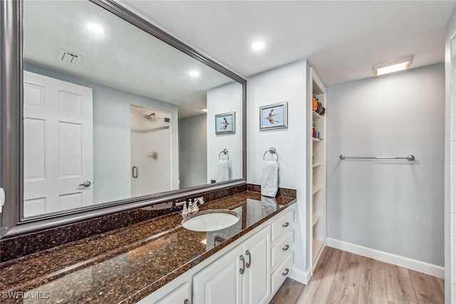 bathroom with wood-type flooring, vanity, and walk in shower