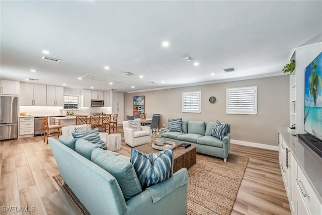 living room featuring sink, crown molding, and light hardwood / wood-style floors